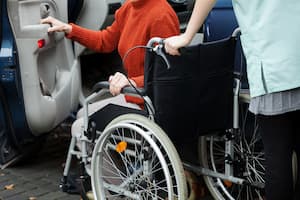 A person in a wheelchair helped onto a transportation vehicle